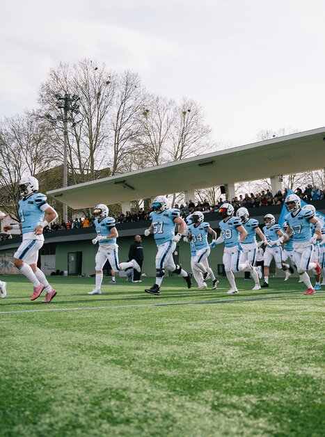A group of football players run onto the field, with spectators in the stands. | © Georg Obetzhofer