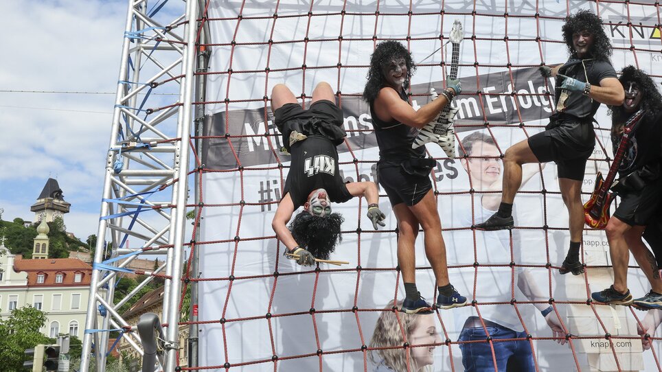 Quattro partecipanti in costume su una struttura di arrampicata durante il Grazathlon. | © GEPA picturesCompanyCode