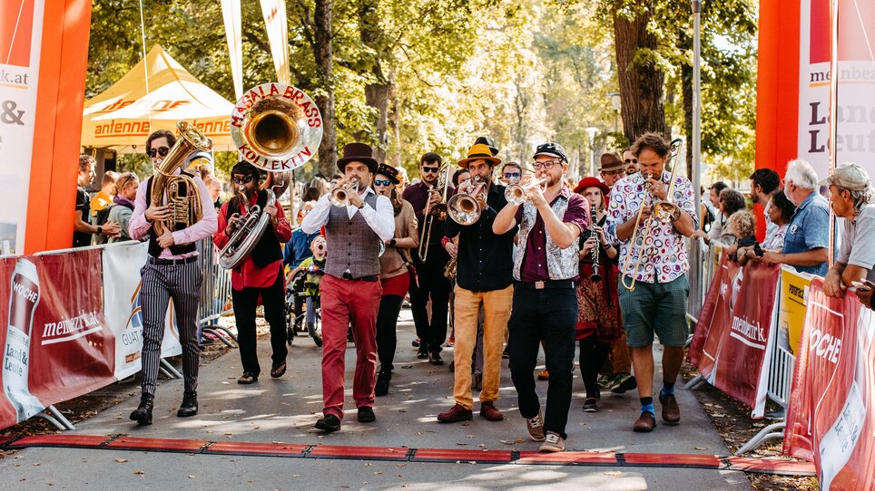 Eine Brassband zieht durch die Straßen von Graz, viele Musiker in bunten Outfits, im Rahmen des Grazer Inklusionslaufs. | © Mario Sudy