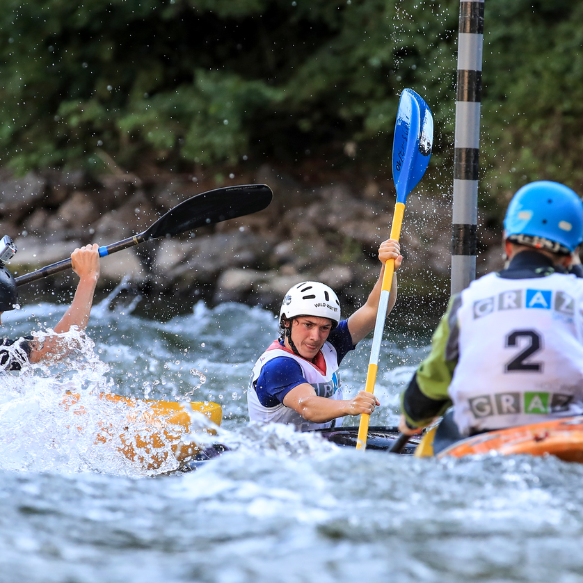 Drei Kajakfahrer auf der Mur während einer Wettkampfveranstaltung in Graz.