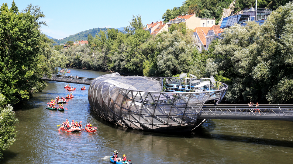 Die Murinsel in Graz mit Paddelbooten auf der Mur.