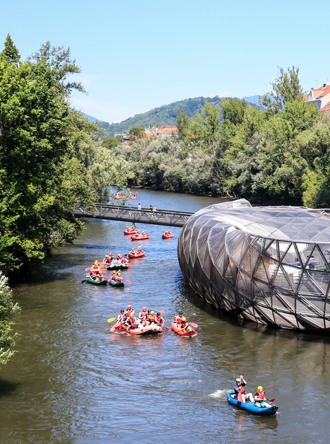 Die Murinsel in Graz mit Paddelbooten auf der Mur.