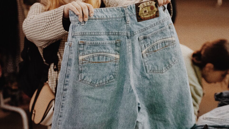 A woman is looking at jeans at a vintage sale. | © BeThrifty