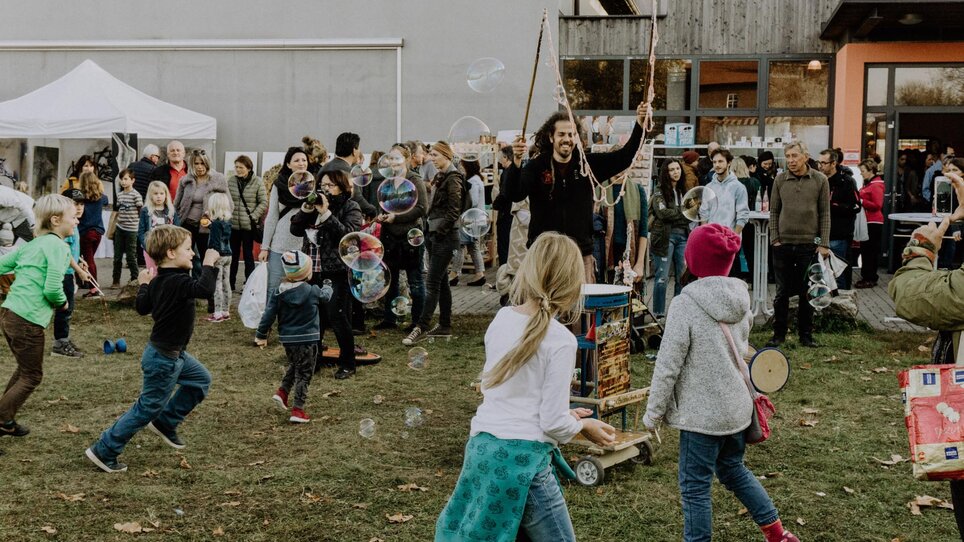 Verschiedene Menschen und Kinder spielen mit Seifenblasen auf einem Markt. | © Kunst- und Designmarkt