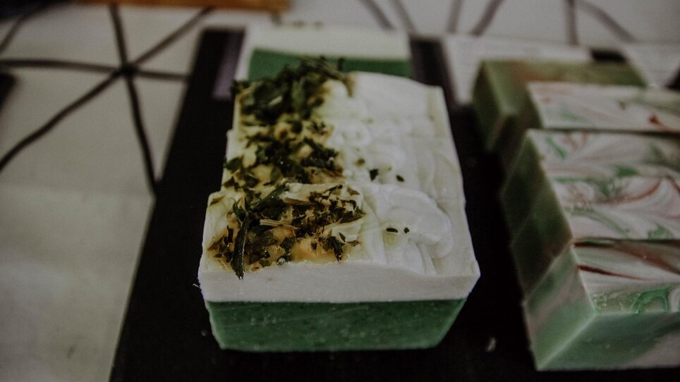 Handgemachte Seifen mit Kräuterdekoration auf einem Tisch. | © Kunst- und Designmarkt