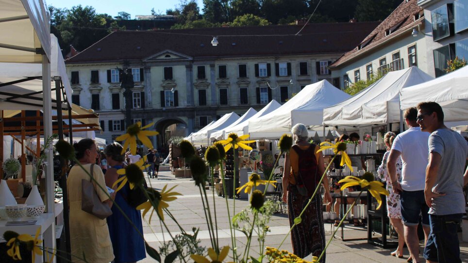 Blick auf den Töpfermarkt mit Ständen und gelben Blumen.
