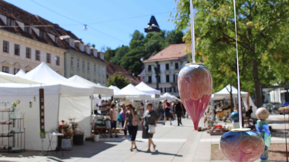 Blick auf den Töpfermarkt in Graz, mit bunten Keramiken und Ständen.