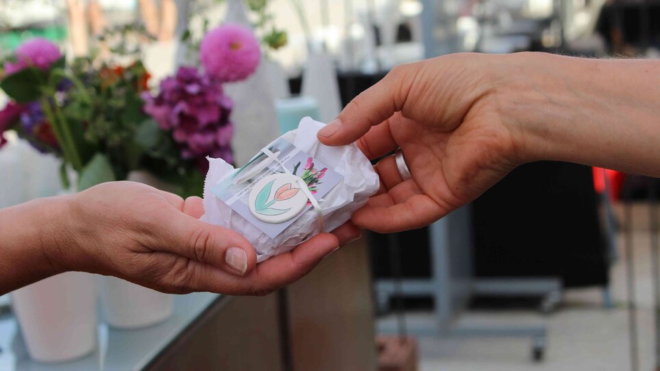 Eine Hand übergibt ein eingepacktes Geschenk auf dem Töpfermarkt.