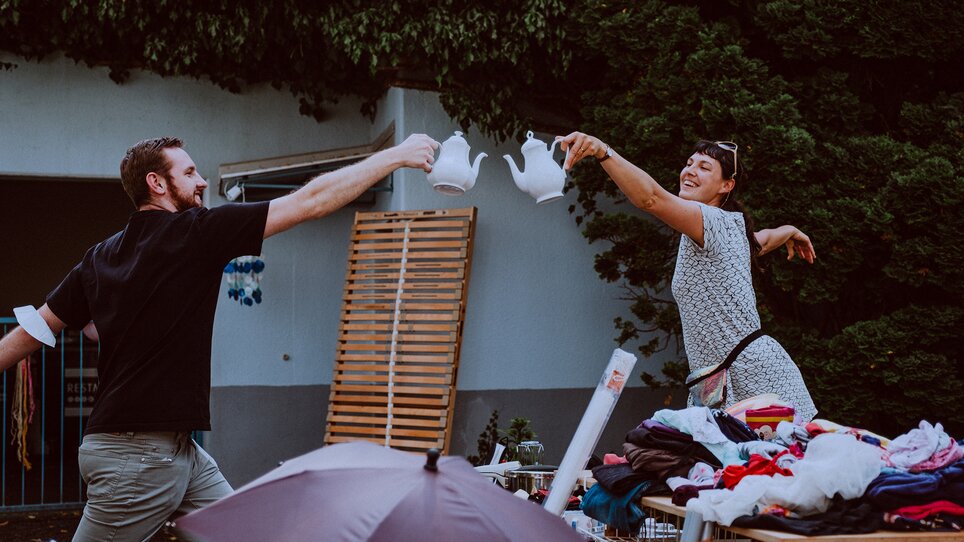 Zwei Personen am Flohmarkt mit Teekannen in der Hand. | © Stella