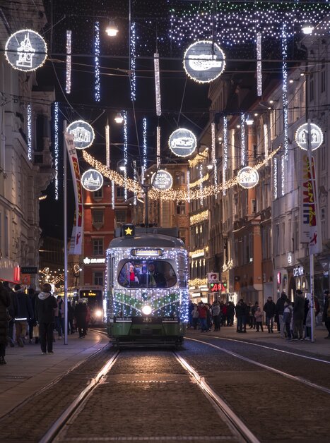 Beleuchtete Straße in Graz mit der Advent-Bim, geschmückt für Weihnachten. | © Vincent Croce