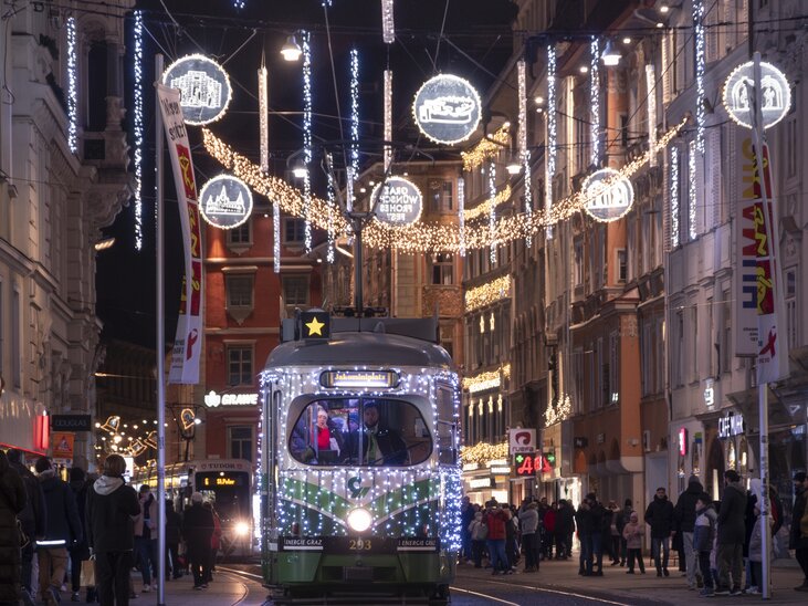 Beleuchtete Straße in Graz mit der Advent-Bim, geschmückt für Weihnachten. | © Vincent Croce