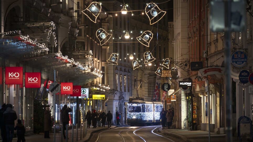 Illuminated streets in Graz with a festively decorated tram and Christmas decorations. | © Vincent Croce