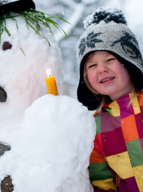 A boy and a snowman holding a candle and sheet music. | © Steirisches Volksliedwerk - Unterrainer