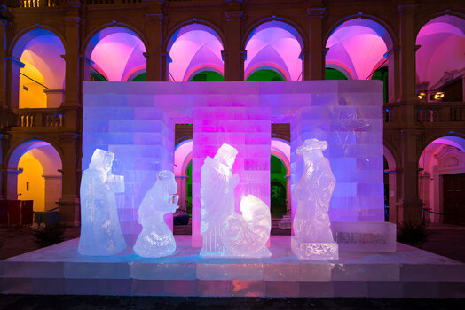 Eiskrippe aus Eis mit buntem Licht, dargestellt im Landhaushof von Graz. | © Graz Tourismus - Harry Schiffer