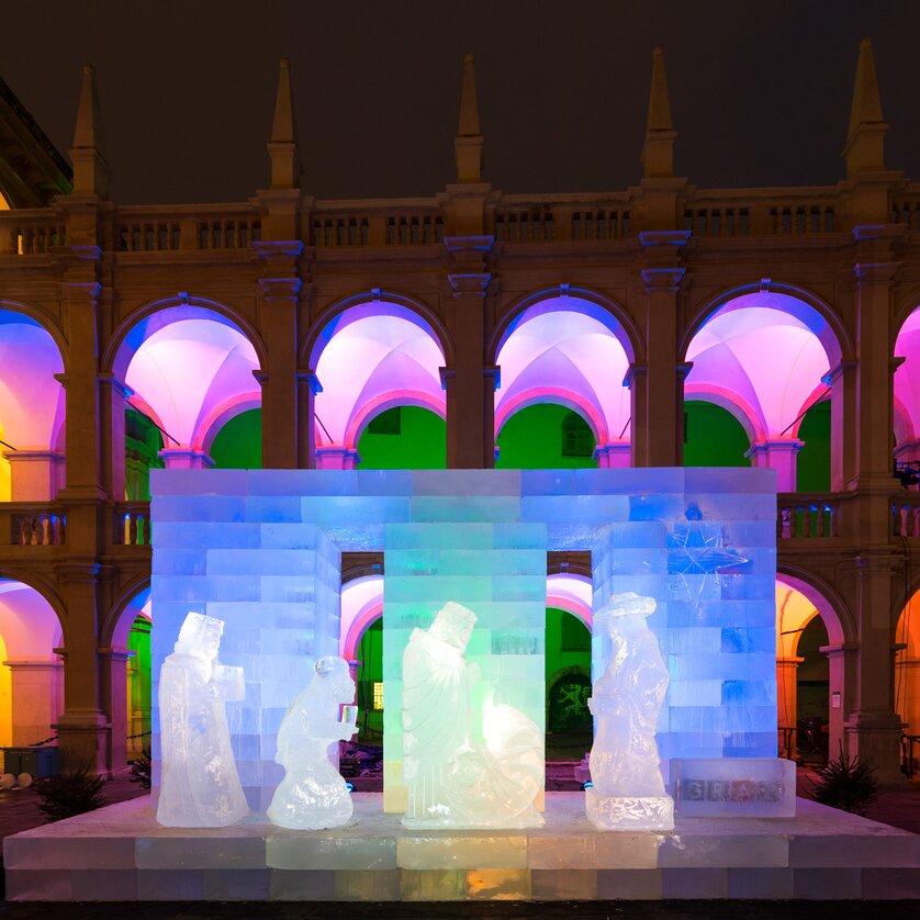Eiskunstwerk einer Krippe im Landhaushof, beleuchtet von bunten Lichtern. | © Graz Tourismus - Harry Schiffer