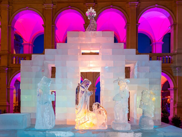 Illuminated ice nativity scene in the Landhaus courtyard of Graz, surrounded by colorful lights. | © Graz Tourismus-Harry Schiffer