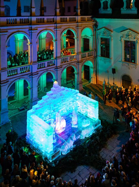 A glowing ice nativity scene in the Landhaus courtyard in Graz, surrounded by spectators. | © Region Graz - Harry Schiffer