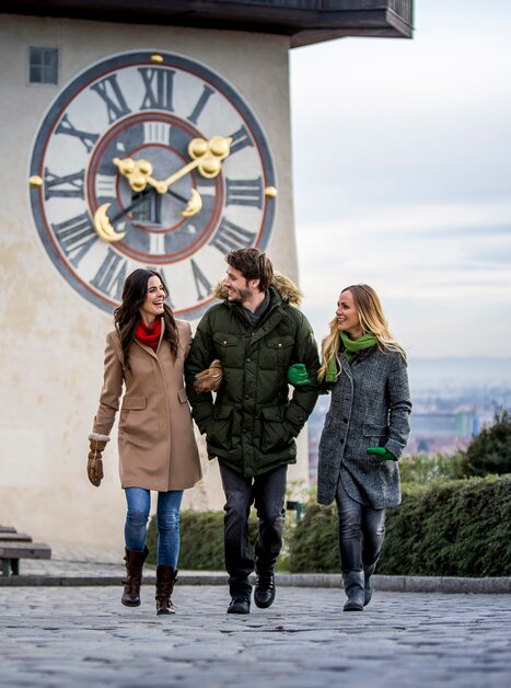 Drei Personen spazieren vor dem Grazer Uhrturm in Graz im Winter. | © Graz Tourismus - Tom Lamm