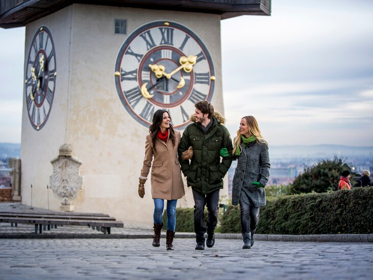 Drei Personen spazieren vor dem Grazer Uhrturm in Graz im Winter. | © Graz Tourismus - Tom Lamm