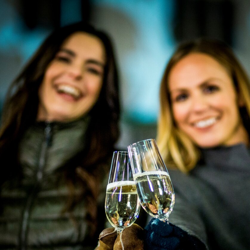 Zwei Frauen halten Sektgläser in der Nacht und lächeln. | © Graz Tourismus - Tom Lamm