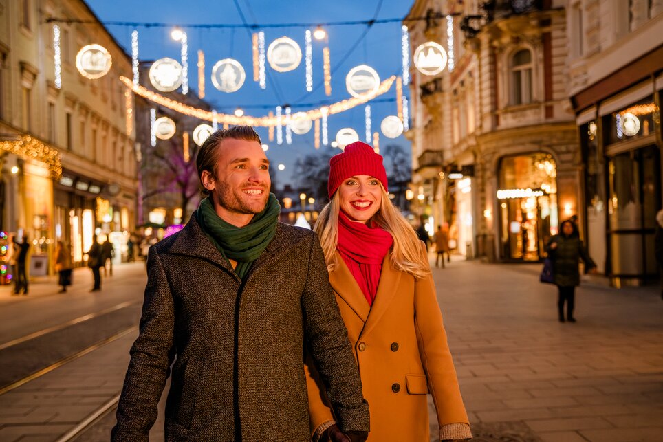 Paar spaziert unter festlicher Beleuchtung in Graz. | © Graz Tourismus - Mias Photoart