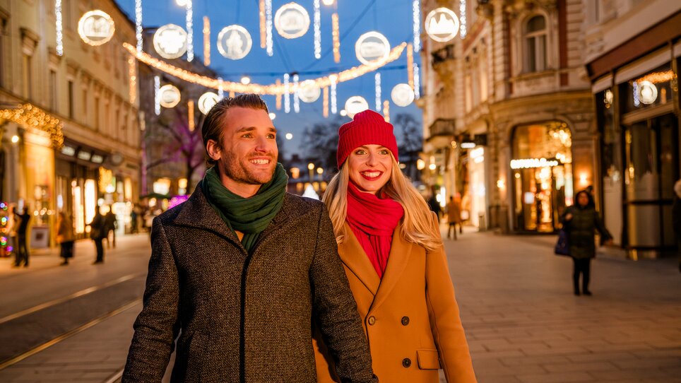 Paar spaziert unter festlicher Beleuchtung in Graz. | © Graz Tourismus - Mias Photoart