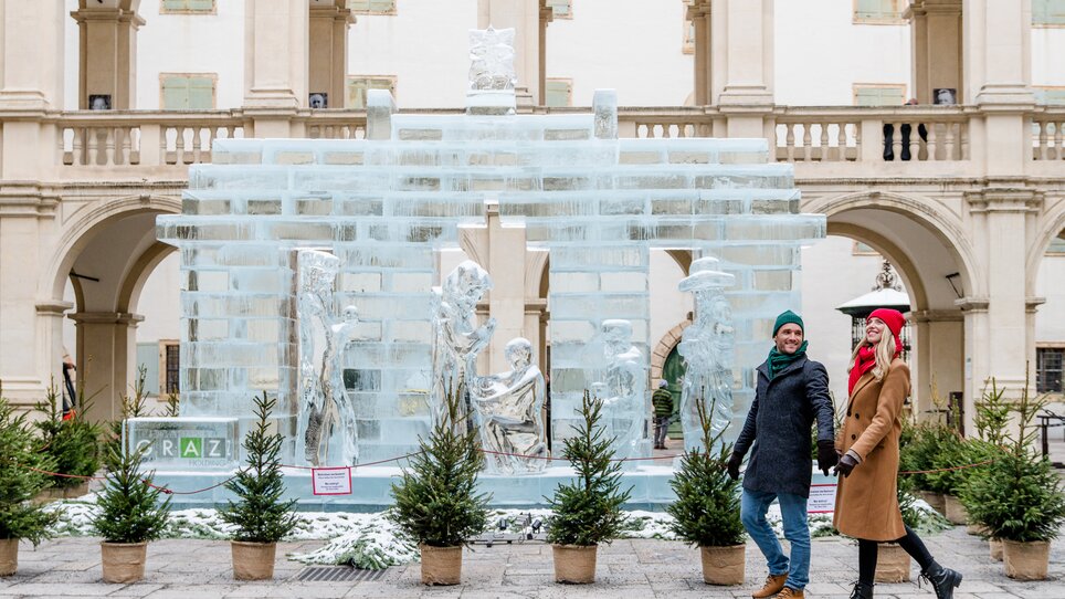 Ein Paar spaziert vor einer imposanten Eisskulptur in Graz. | © Graz Tourismus - Mias Photoart