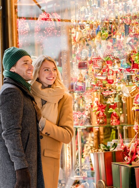 Una coppia ammira decorazioni natalizie festive in una vetrina. | © Graz Tourismus - Mias Photoart