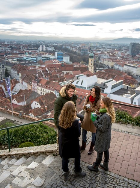 Group of friends enjoying the view over Graz from the Schlossberg. | © Graz Tourismus - Tom Lamm
