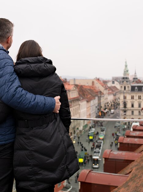 Coppia che guarda da una terrazza il panorama dei tetti di Graz e il municipio. | © Graz Tourismus - Katja Stadler