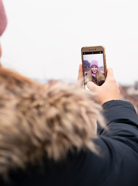 A person takes a selfie with Graz in the background on a cloudy day. | © Graz Tourismus - Katja Stadler