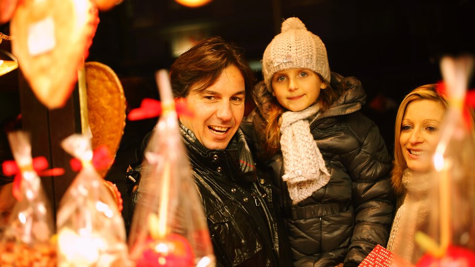 Eine Familie vor einem Marktstand voller Süßigkeiten und Leckereien. | © Graz Tourismus - Max Wegscheidler
