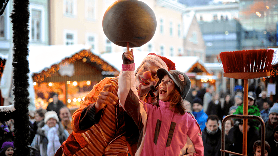 Ein Clown und ein Mädchen jonglieren gemeinsam auf einem Weihnachtsmarkt in Graz. | © Foto Jakotopia