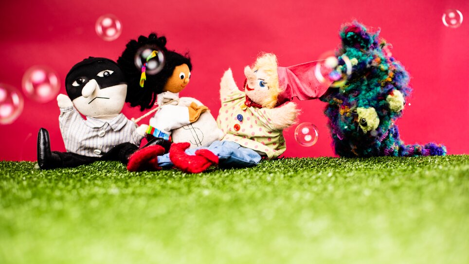 Vier bunte Puppen auf grünem Gras, umgeben von Seifenblasen. | © Kasperl larifari