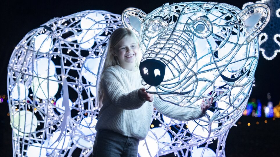 Ein Mädchen steht neben einer beleuchteten Eisbärenfigur. | © Mathias Kniepeiss