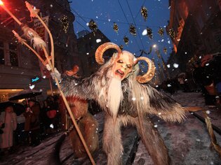 Perchten parade through snowy Graz, amidst festive lights. | © Graz Tourismus - Harry Schiffer