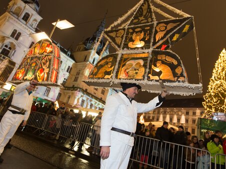 People in white suits carry elaborate lanterns during the Krampus and Perchten procession in Graz, surrounded by spectators and festive lights. | © Graz Tourismus - Harry Schiffer