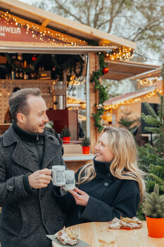 Couple in winter clothing enjoying mulled wine at the advent market. | © Mias Photoart
