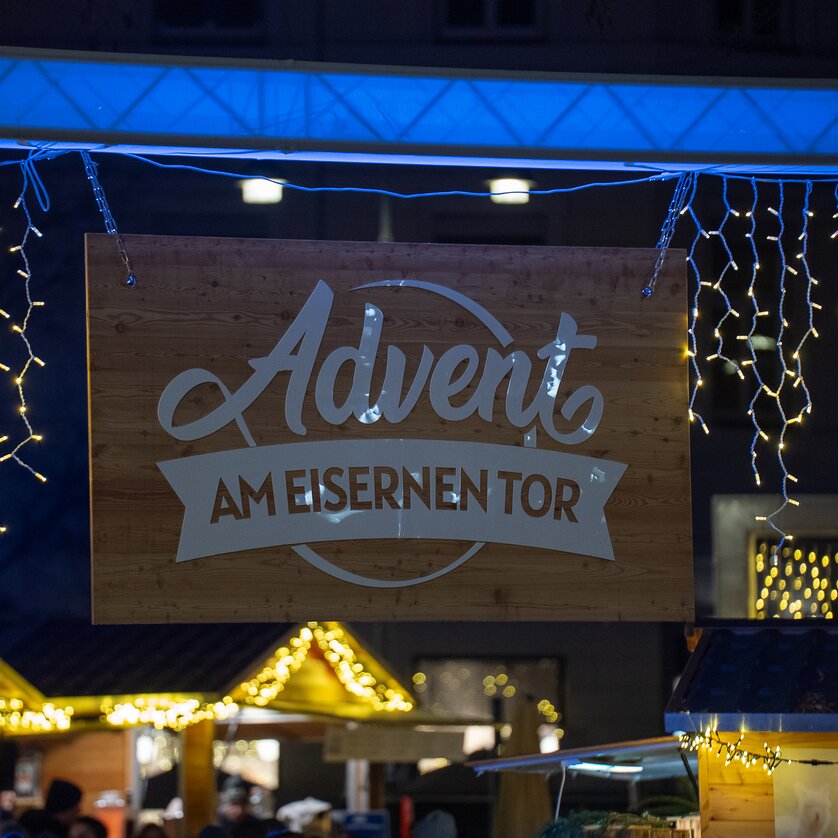 Lichter und das Schild mit dem Schriftzug "Advent am Eisernen Tor" bei einem Weihnachtsmarkt in Graz. | © Peter Hutter