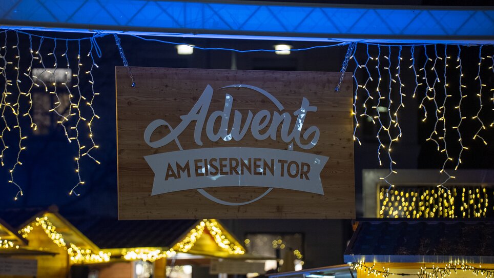 Lichter und das Schild mit dem Schriftzug "Advent am Eisernen Tor" bei einem Weihnachtsmarkt in Graz. | © Peter Hutter