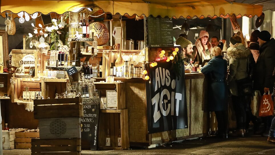 Ein festlicher Marktstand mit Lichtern, Getränken und Dekorationen auf dem Freiheitsplatz in Graz. | © Thomas Luef