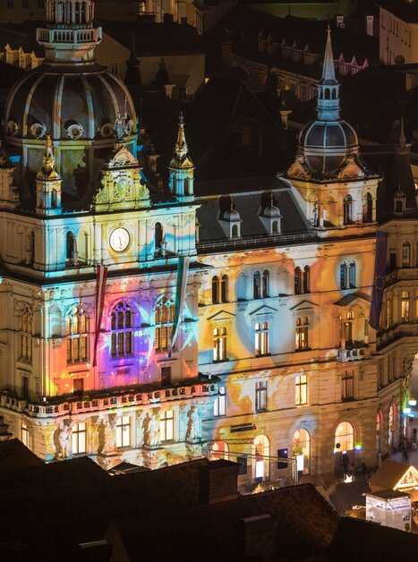 Illuminated town hall in Graz at the Christmas market with colorful lights and decorations. | © Graz Tourismus - Harry Schiffer