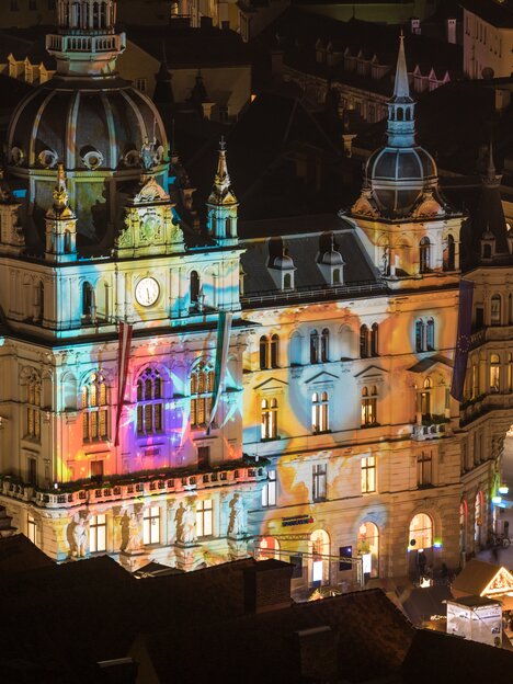 Illuminated town hall in Graz at the Christmas market with colorful lights and decorations. | © Graz Tourismus - Harry Schiffer