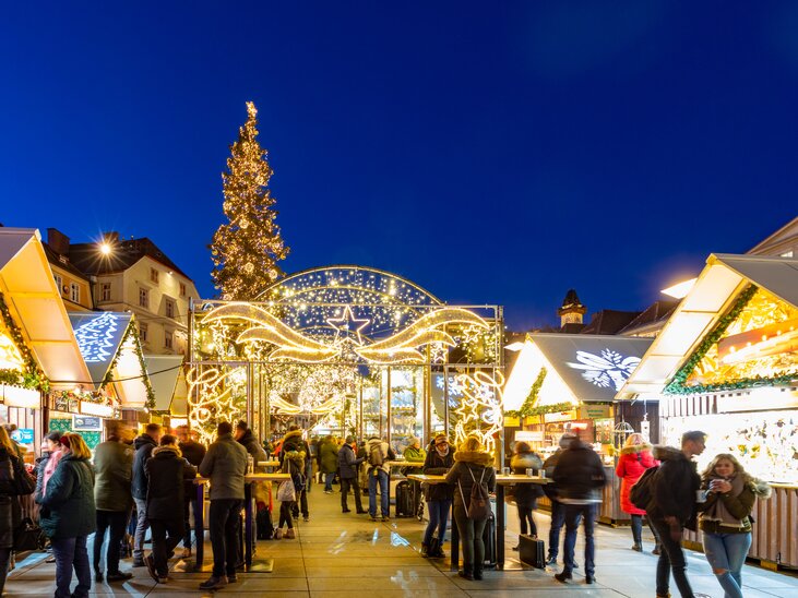 Christmas market in Graz with festive lighting, decorated stalls, and a large Christmas tree. | © Graz Tourismus - Harry Schiffer