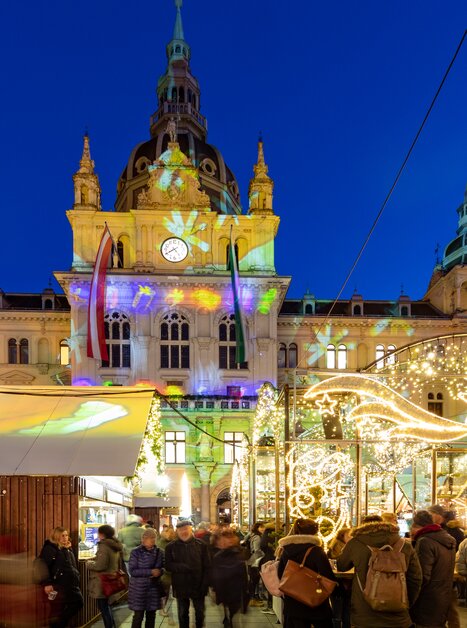 Beleuchteter Christkindlmarkt mit Menschen vor dem Grazer Rathaus zur Weihnachtszeit. | © Graz Tourismus - Harry Schiffer