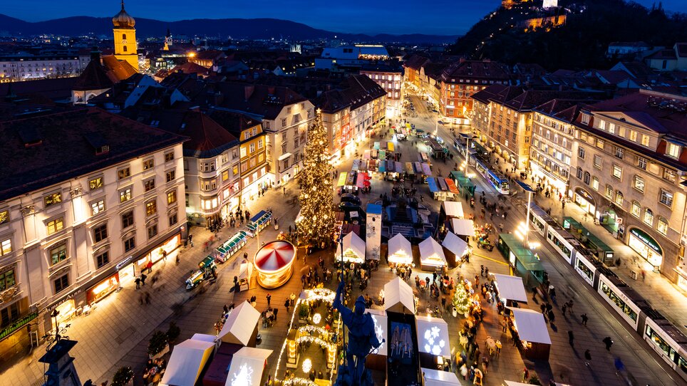 Illuminated Christmas market with stalls and Christmas tree in Graz. | © Graz Tourismus-Harry Schiffer