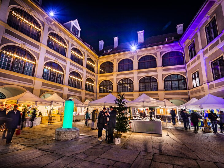 Beleuchteter Innenhof im Joanneumsviertel mit Ständen und Besuchern bei Nacht. | © Graz Tourismus - Werner Krug