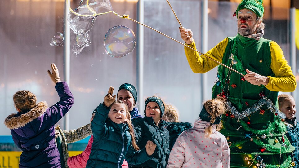 Children ice skating around a Christmas-themed character. | © Kuro Simon