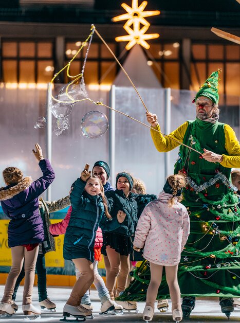 Children ice skating around a Christmas-themed character. | © Kuro Simon