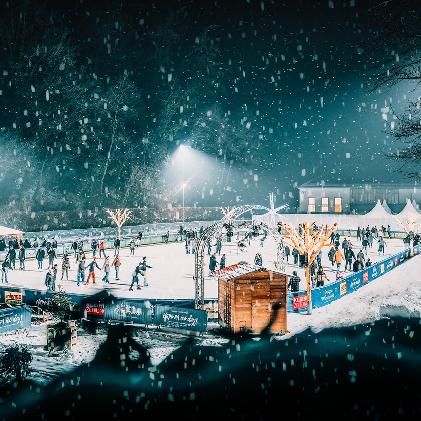 Winter scene at the ice skating rink in Graz, featuring numerous skaters and festive lights. | © Stefan Leitner